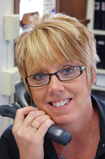 Image of Customer Service Representative smiling with telephone. 